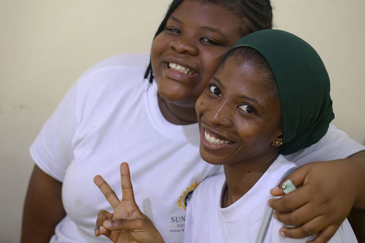 Two young participants smiling with their arms around each other at the Teens Summit