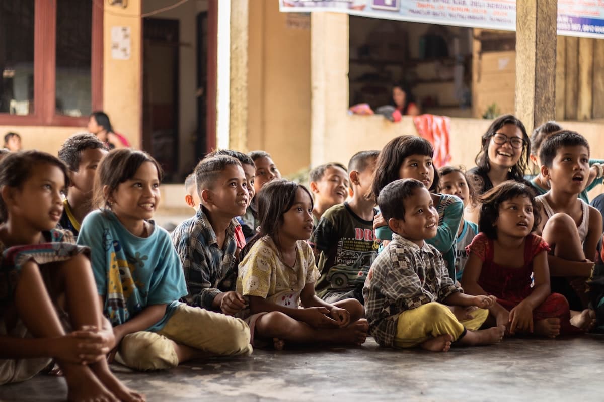 Children sitting together with a caregiver, listening attentively and smiling