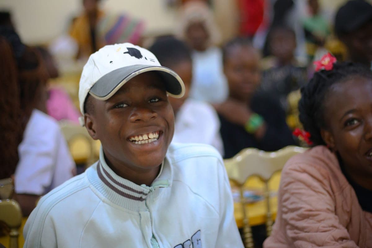 A young boy smiling brightly among other children at a Sunflower Foundation session