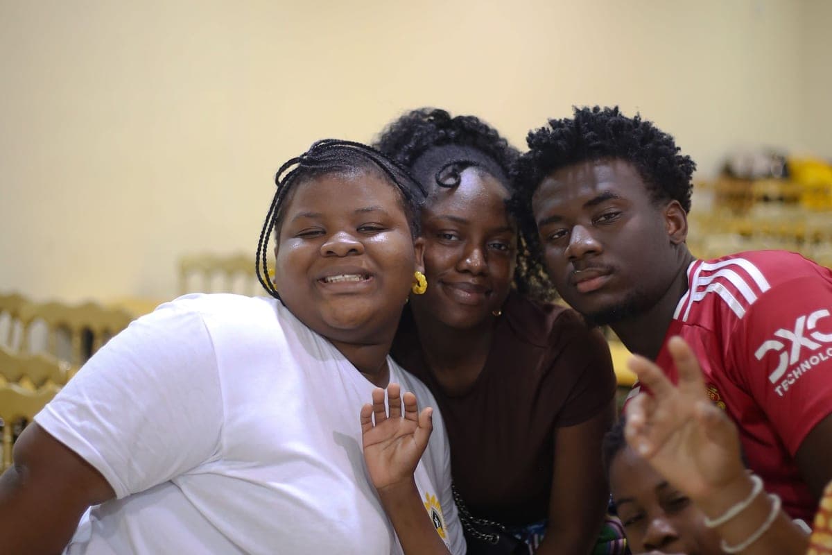 Three teenagers leaning in together and smiling at a Sunflower Foundation event