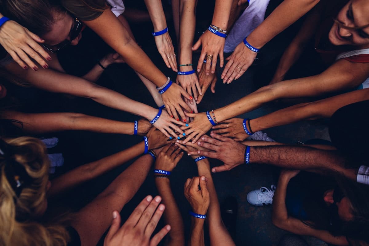 Many hands resting together on a tree trunk, symbolising community
