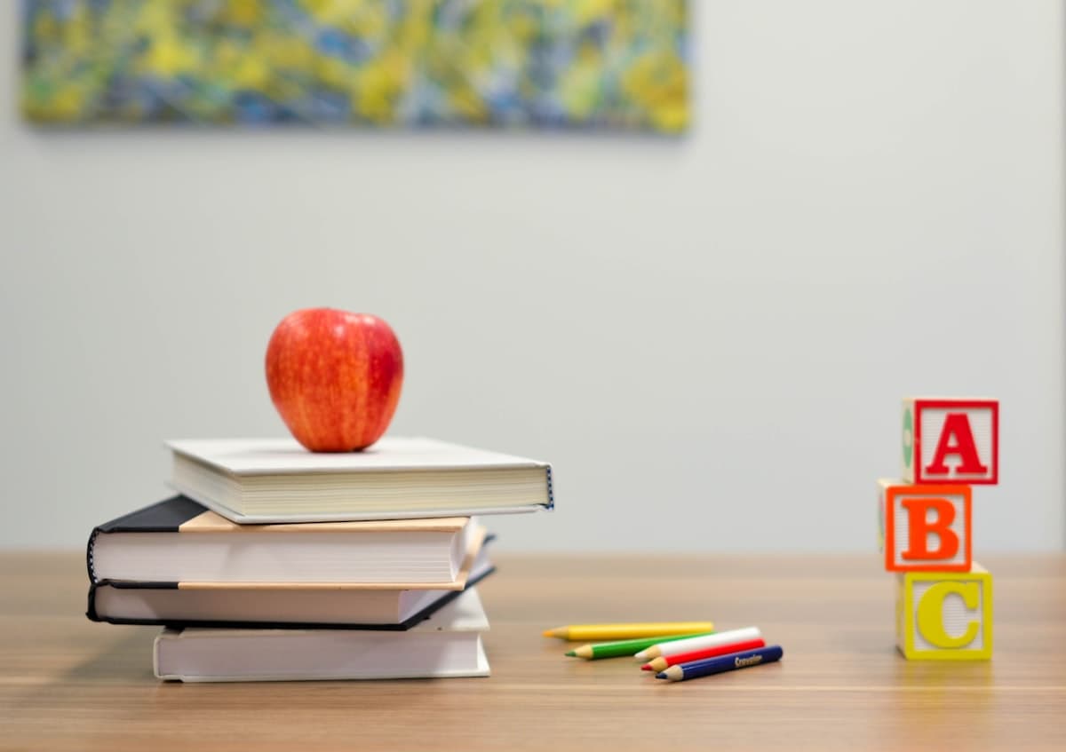 School books, pencils and alphabet blocks on a classroom desk